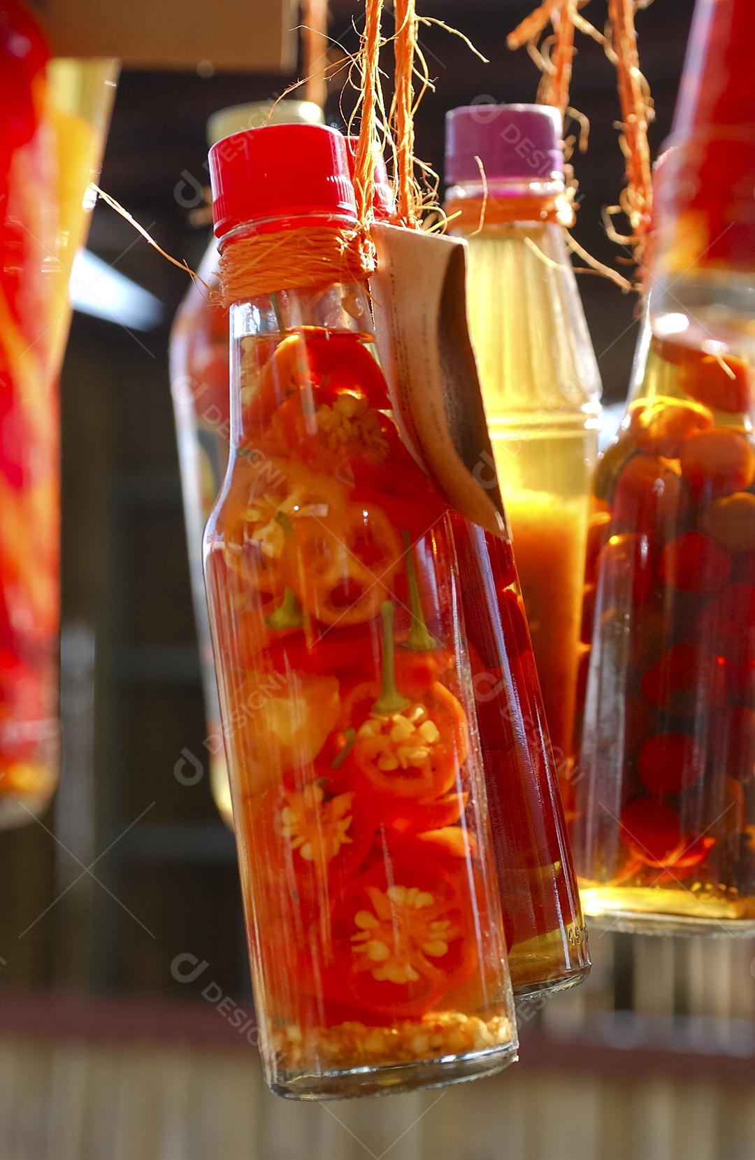 Pimenta artesanal em garrafas de vidro à venda em uma feira popular no Brasil.