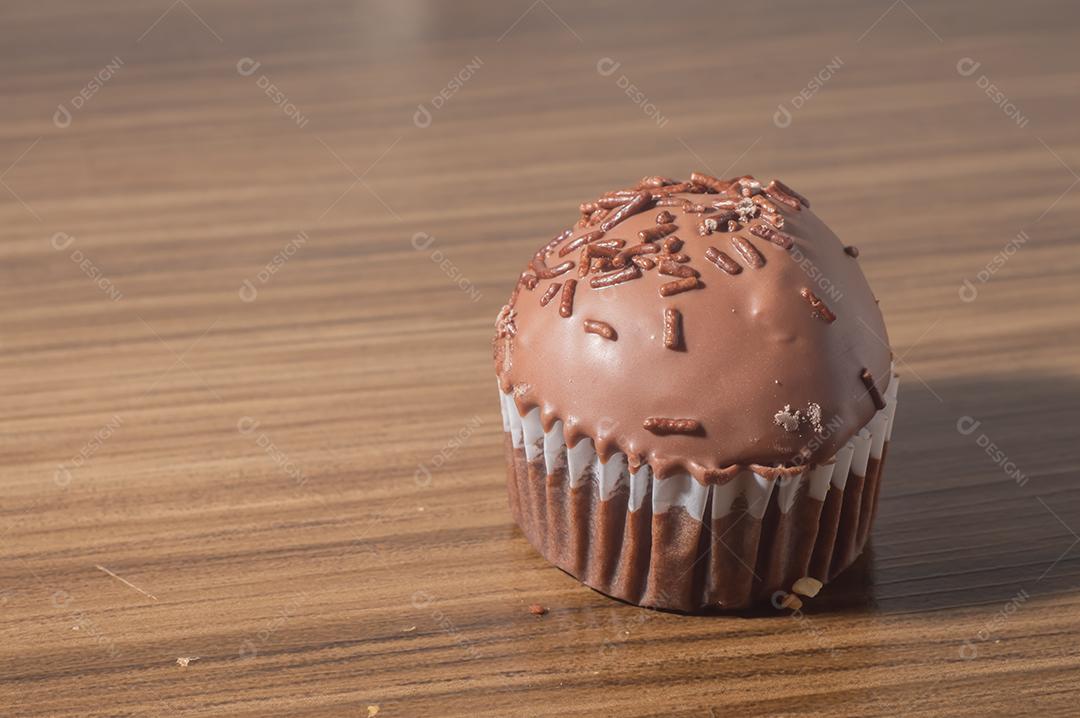 Bolinho de chocolate, muffin de chocolate com castanhas, em uma mesa de madeira