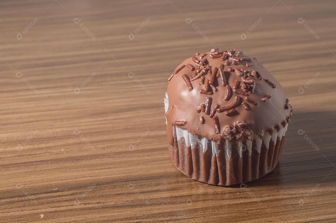 Bolinho de chocolate, muffin de chocolate com castanhas, em uma mesa de madeira