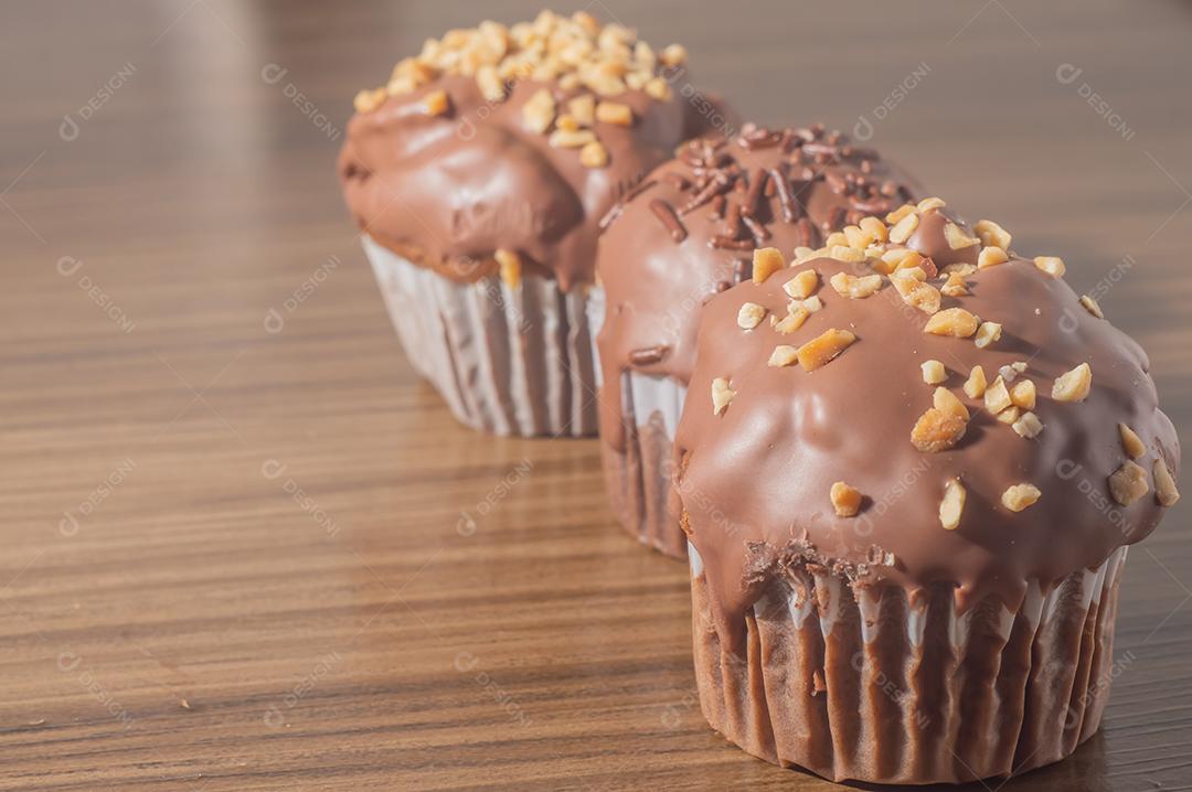 Bolinho de chocolate, muffin de chocolate com castanhas, em uma mesa de madeira