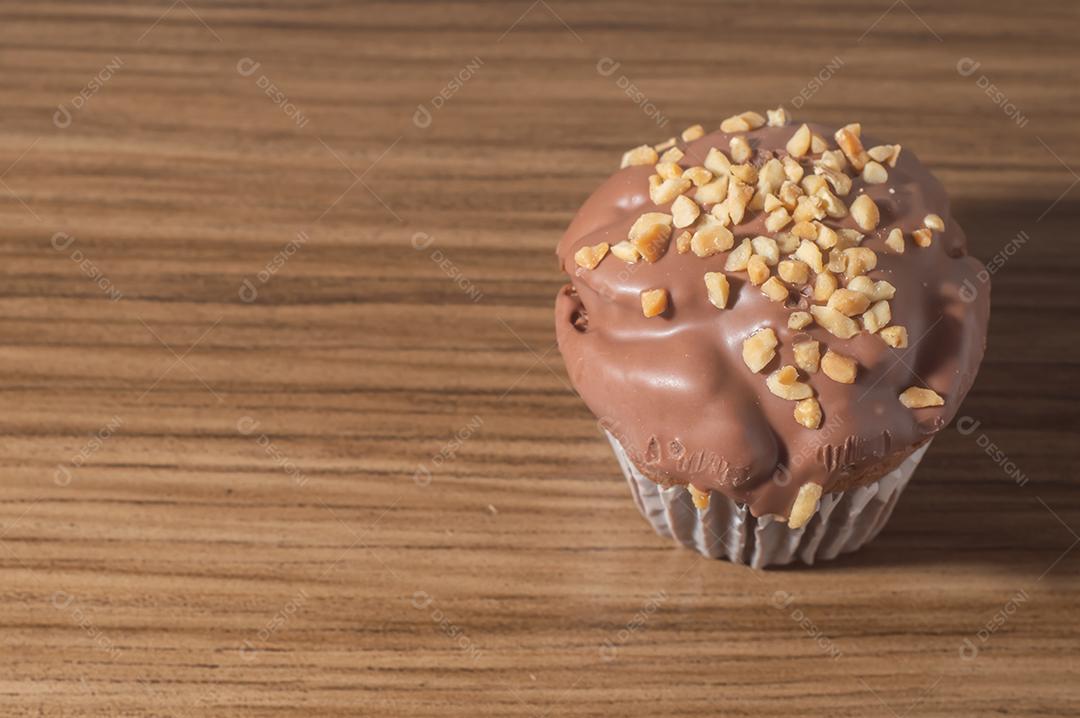 Bolinho de chocolate, muffin de chocolate com castanhas, em uma mesa de madeira