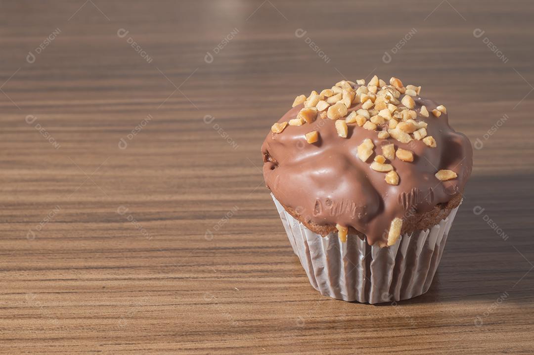 Bolinho de chocolate, muffin de chocolate com castanhas, em uma mesa de madeira