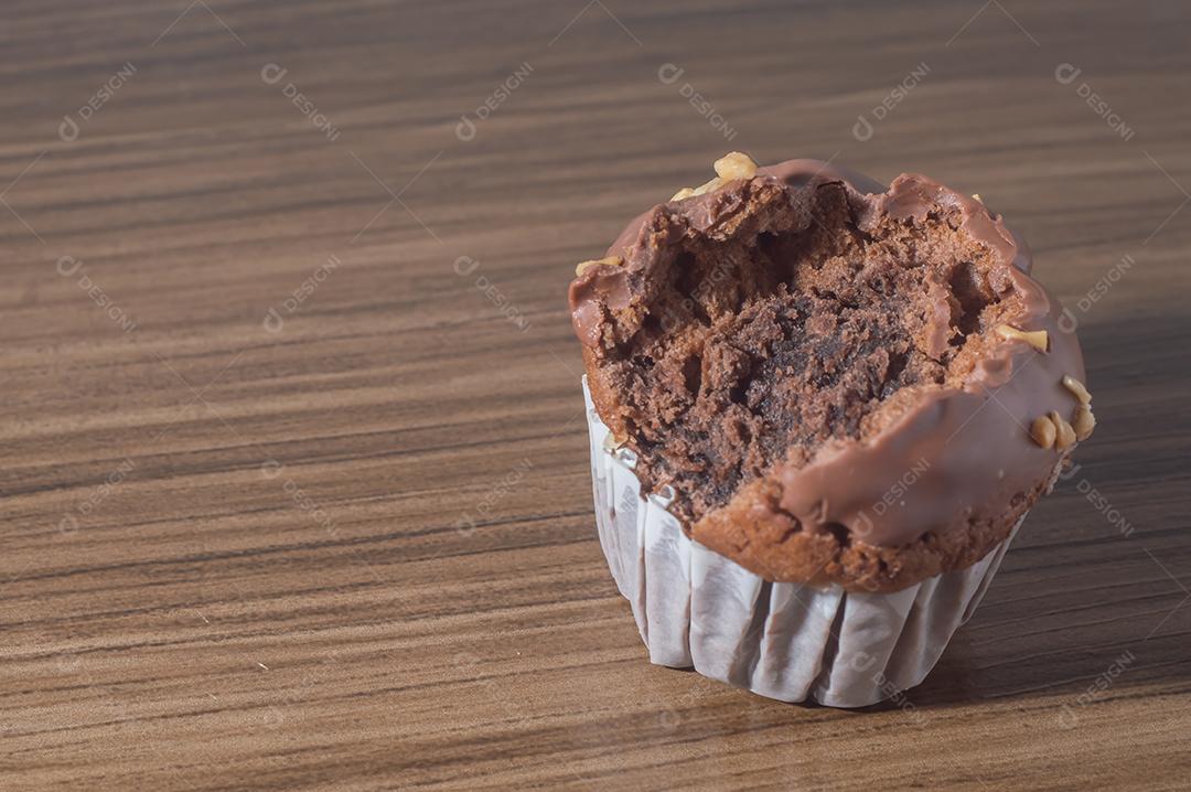 Bolinho de chocolate, muffin de chocolate com castanhas, em uma mesa de madeira