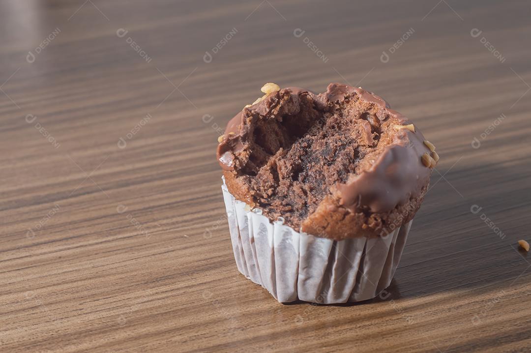 Bolinho de chocolate, muffin de chocolate com castanhas, em uma mesa de madeira
