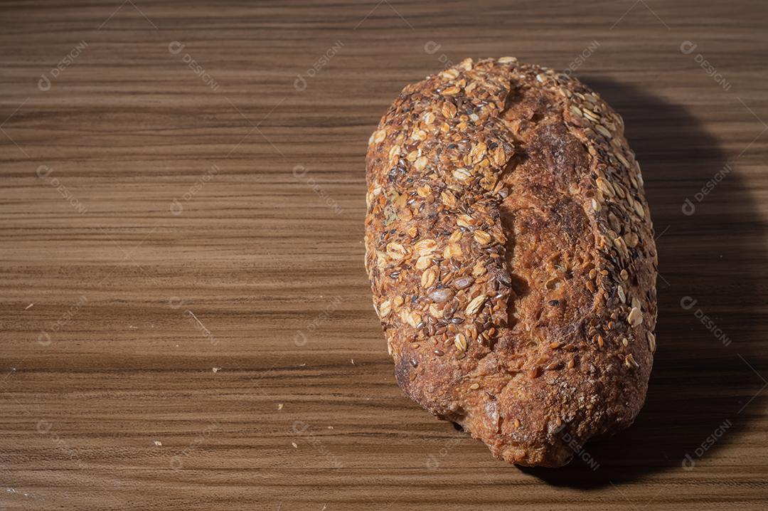 Fatia de pão de centeio integral com sementes, pão multigrãos em uma mesa de madeira com espaço de cópia.