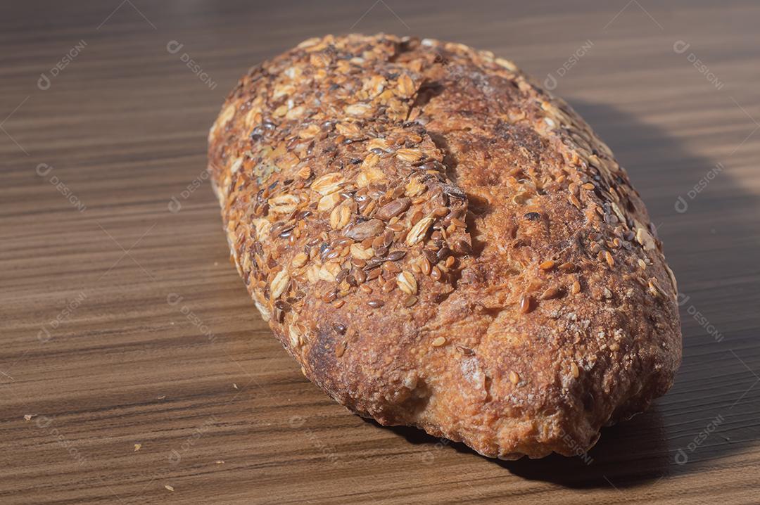 Fatia de pão de centeio integral com sementes, pão multigrãos em uma mesa de madeira com espaço de cópia.