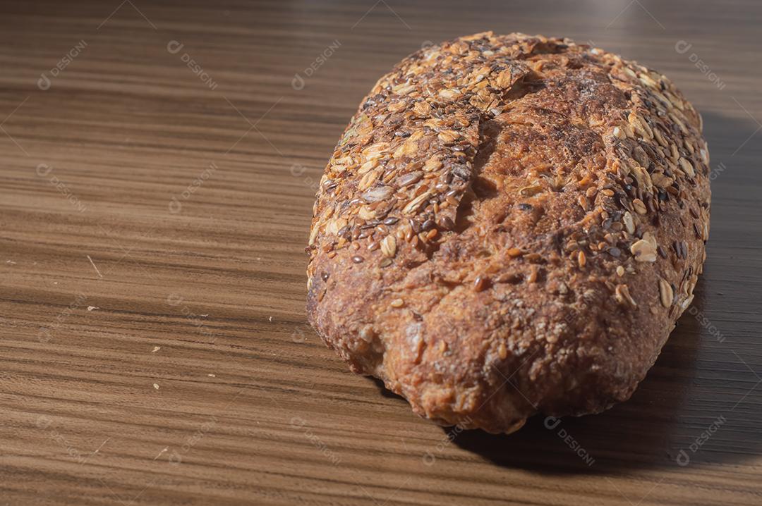 Fatia de pão de centeio integral com sementes, pão multigrãos em uma mesa de madeira com espaço de cópia.