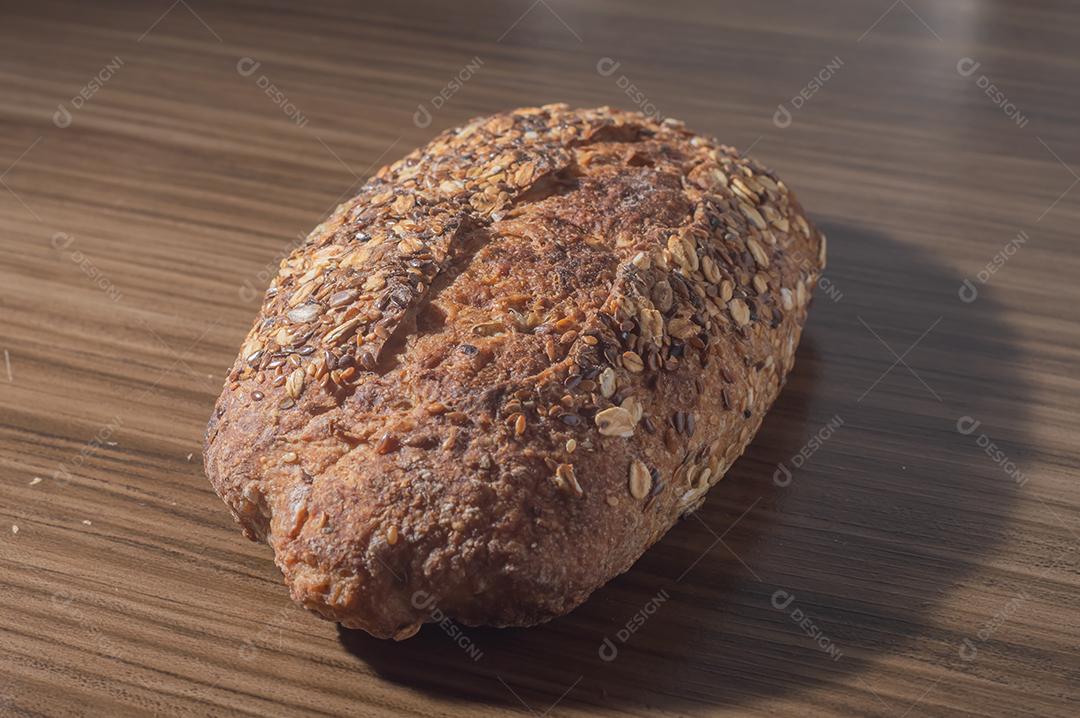 Fatia de pão de centeio integral com sementes, pão multigrãos em uma mesa de madeira com espaço de cópia.