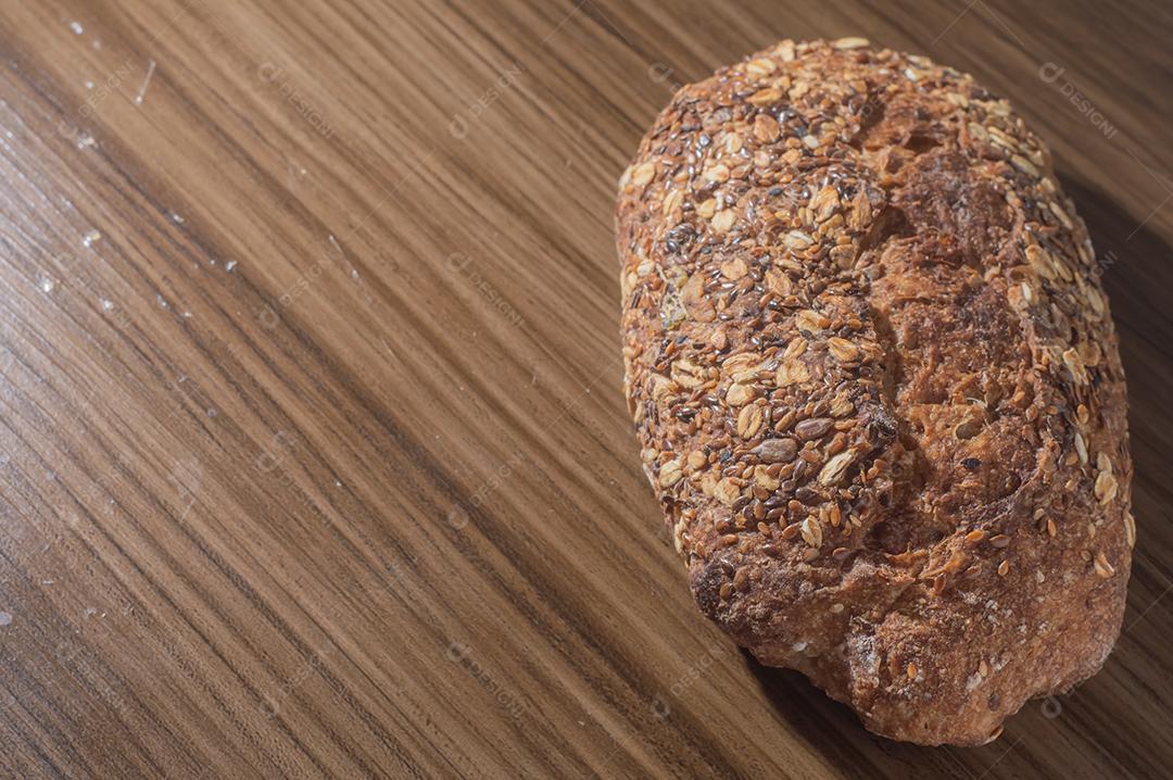 Fatia de pão de centeio integral com sementes, pão multigrãos em uma mesa de madeira com espaço de cópia.