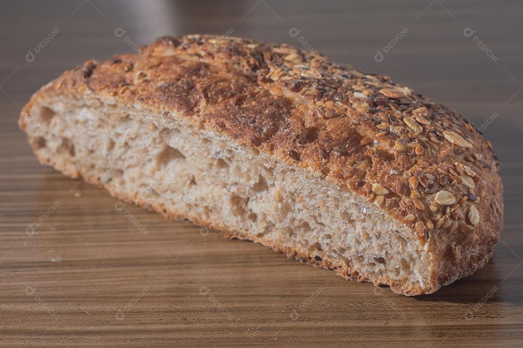 Fatia de pão de centeio integral com sementes, pão multigrãos em uma mesa de madeira com espaço de cópia.