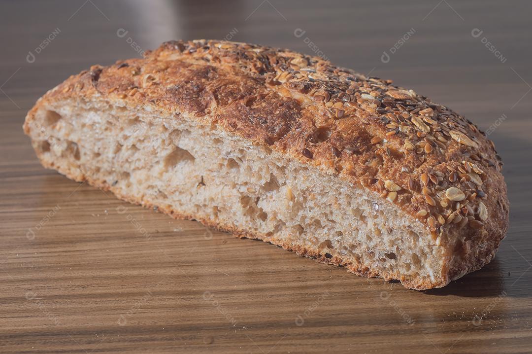 Fatia de pão de centeio integral com sementes, pão multigrãos em uma mesa de madeira com espaço de cópia.