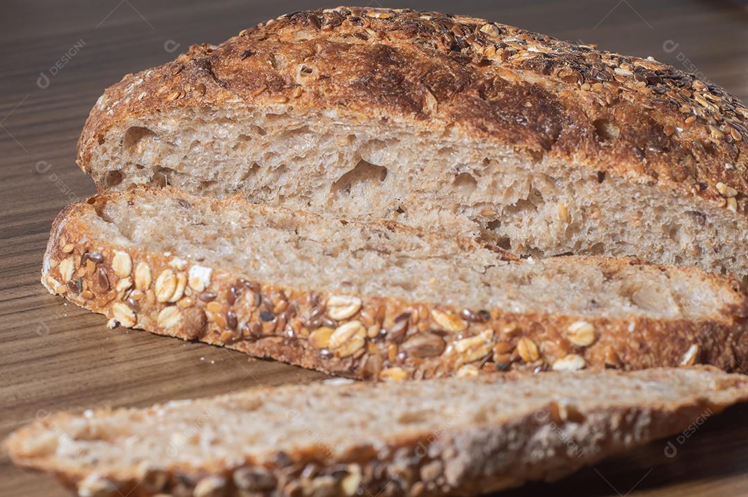 Fatia de pão de centeio integral com sementes, pão multigrãos em uma mesa de madeira com espaço de cópia.