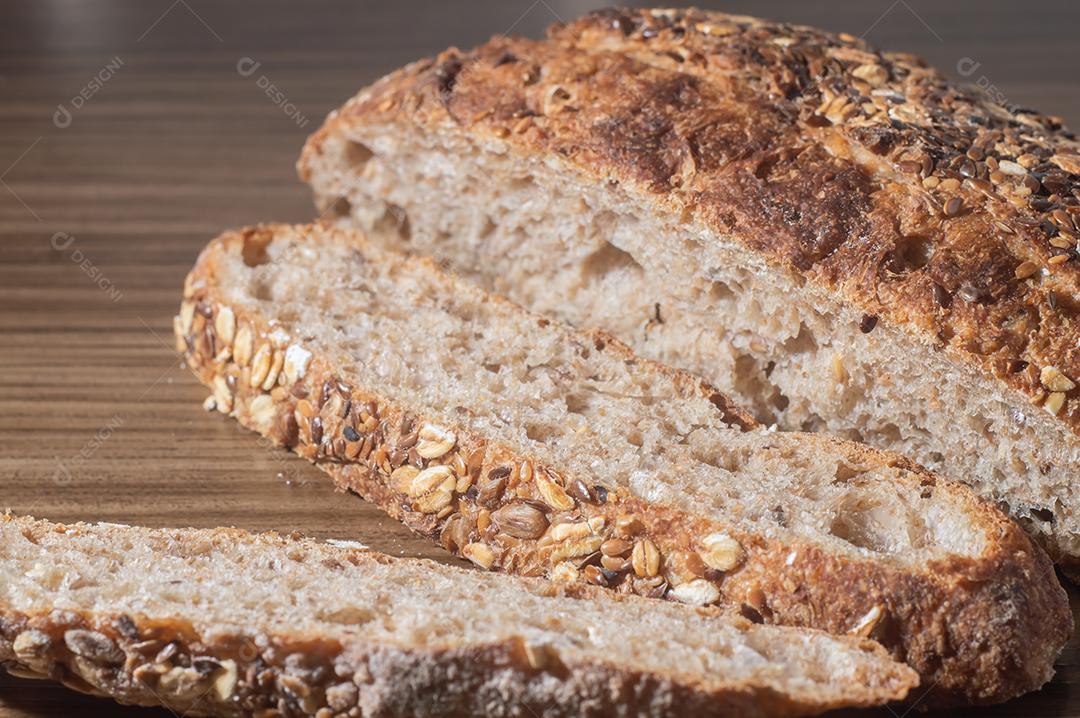 Fatia de pão de centeio integral com sementes, pão multigrãos em uma mesa de madeira com espaço de cópia.