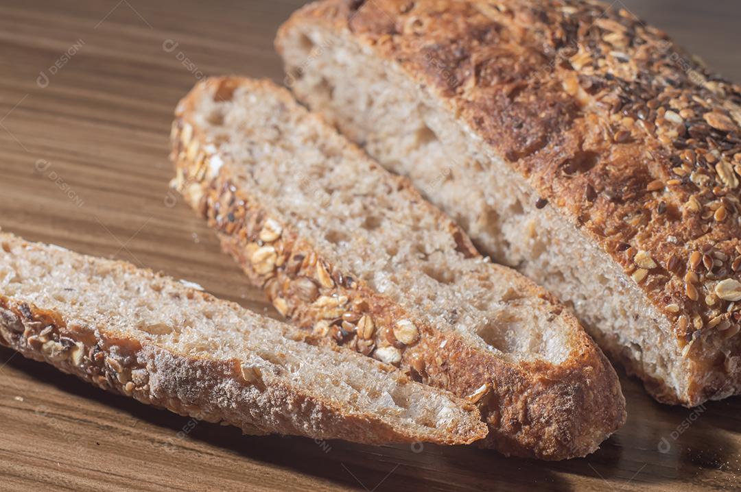 Fatia de pão de centeio integral com sementes, pão multigrãos em uma mesa de madeira com espaço de cópia.
