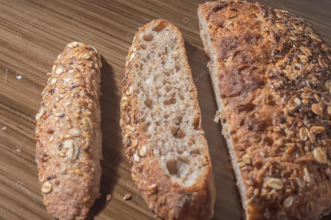 Fatia de pão de centeio integral com sementes, pão multigrãos em uma mesa de madeira com espaço de cópia.