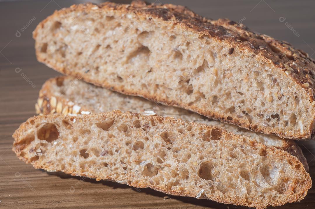 Fatia de pão de centeio integral com sementes, pão multigrãos em uma mesa de madeira com espaço de cópia.