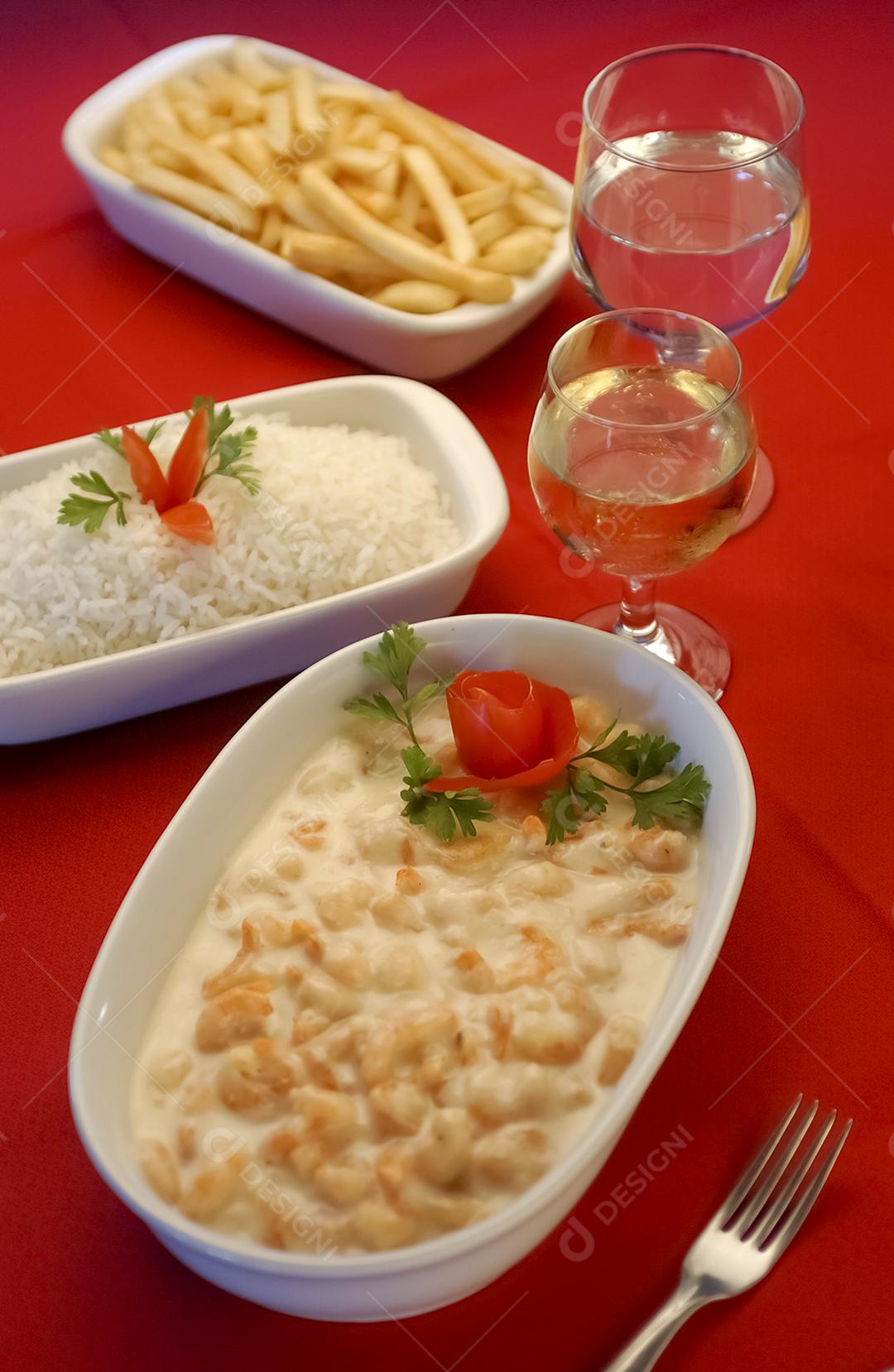 Camarão em molho de queijo branco em tigela branca na toalha de mesa vermelha.