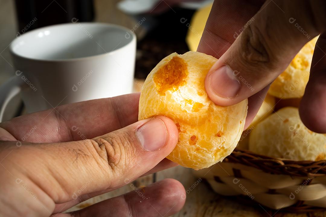 homem pegando pãõ de queijo