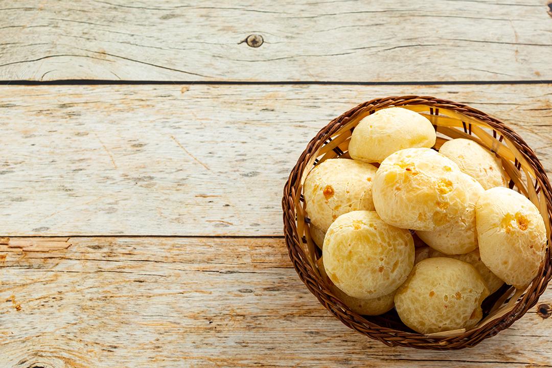 pãõ de queijo em cestinha de madeira em mesa de madeira