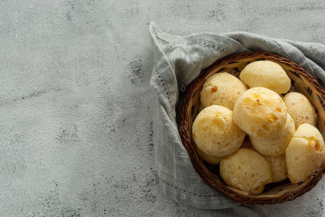 pãõ de queijo em cestinha de madeira em superficie de pedra