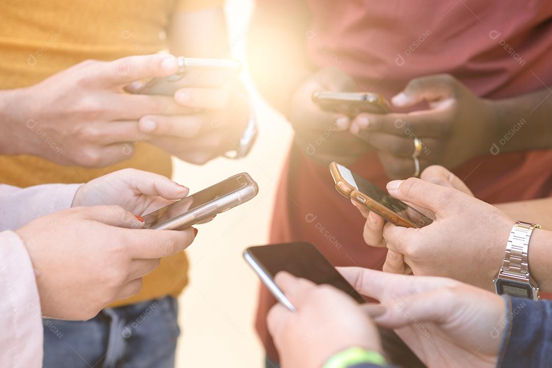 Grupo de jovens usando seus telefones ao ar livre. Conceito de educação, tecnologia e felicidade