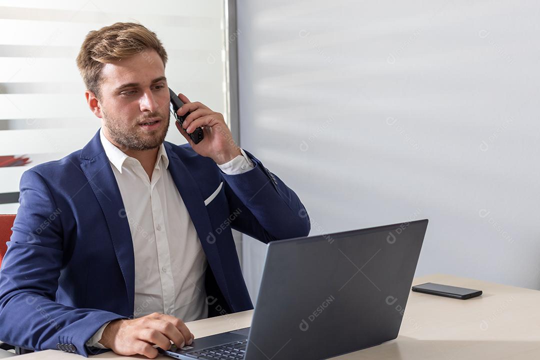 homem de negócios jovem na mesa em frente ao computador e telefone celular