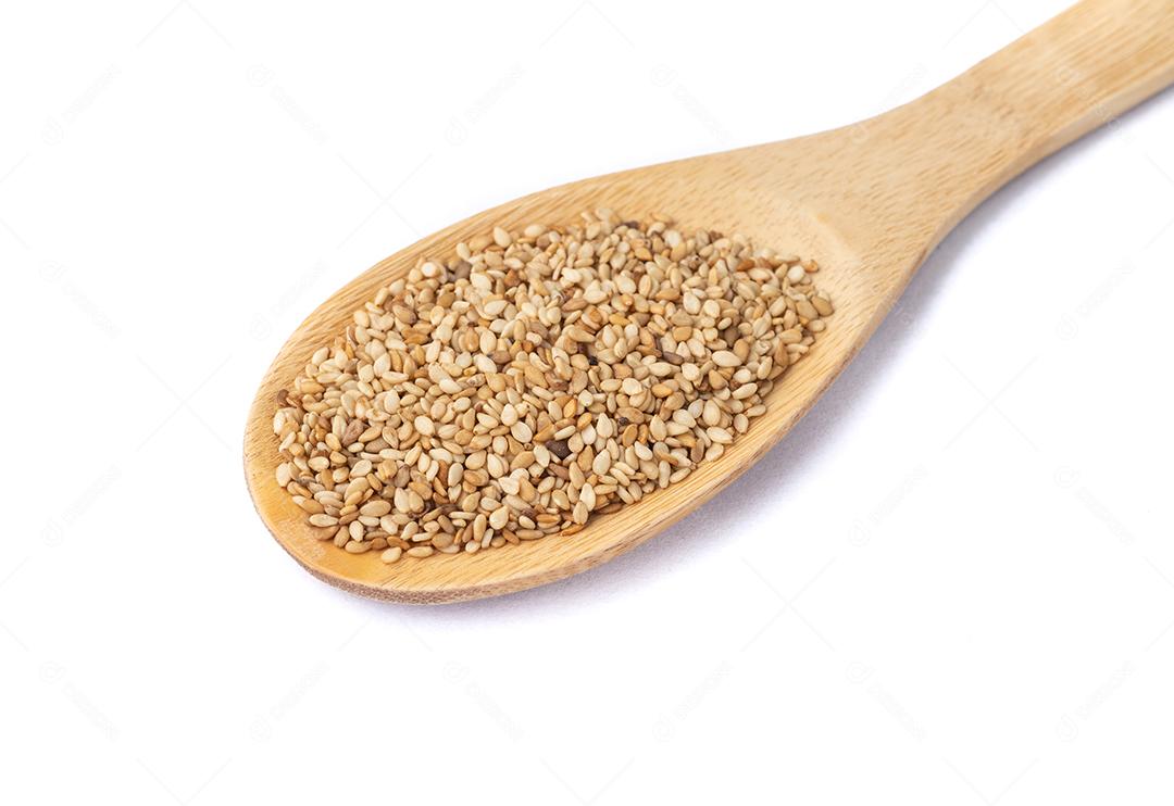Sementes de gergelim em uma colher isolada sobre fundo branco.