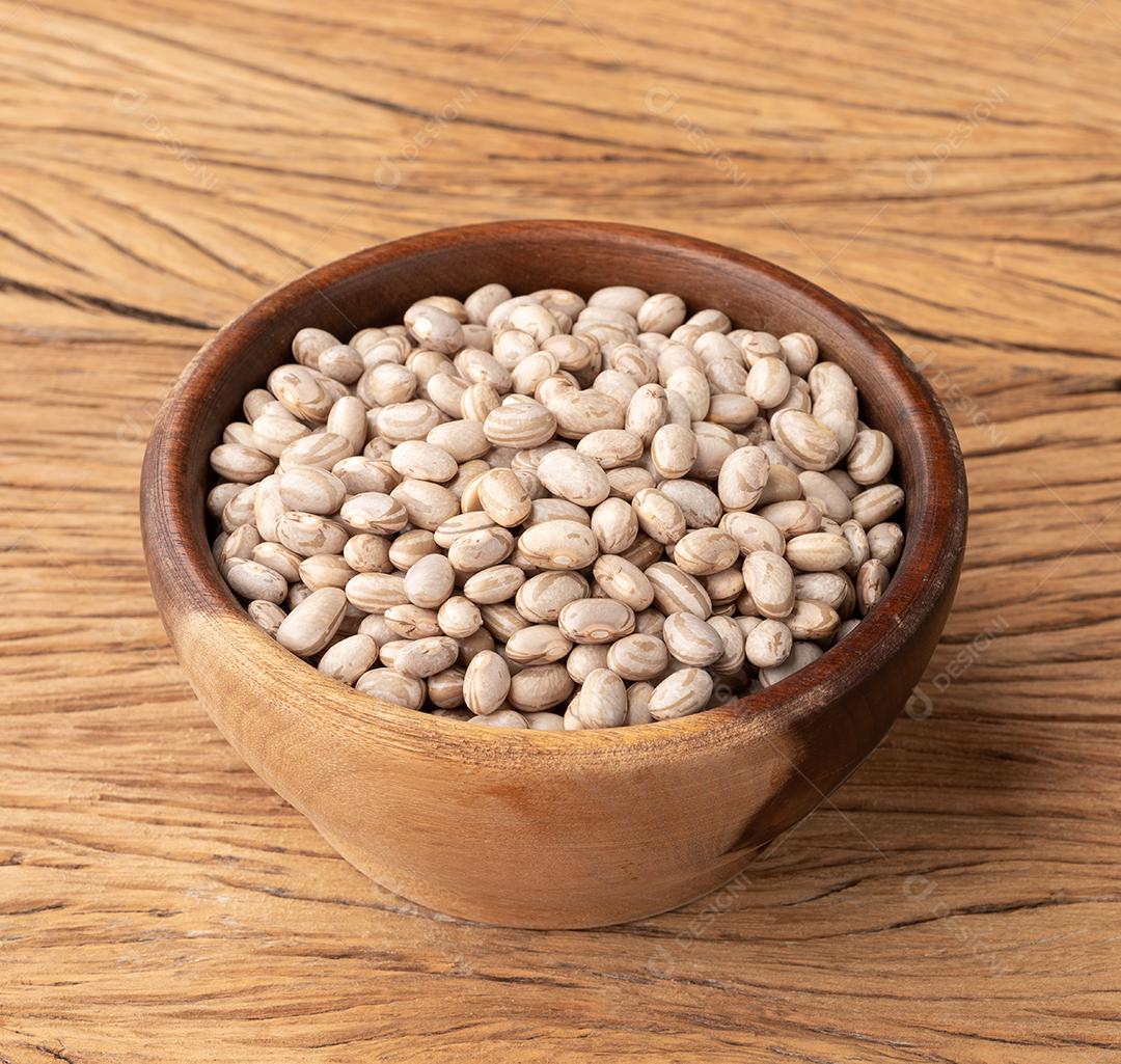 Feijão marrom cru em uma tigela de madeira sobre a mesa de madeira.
