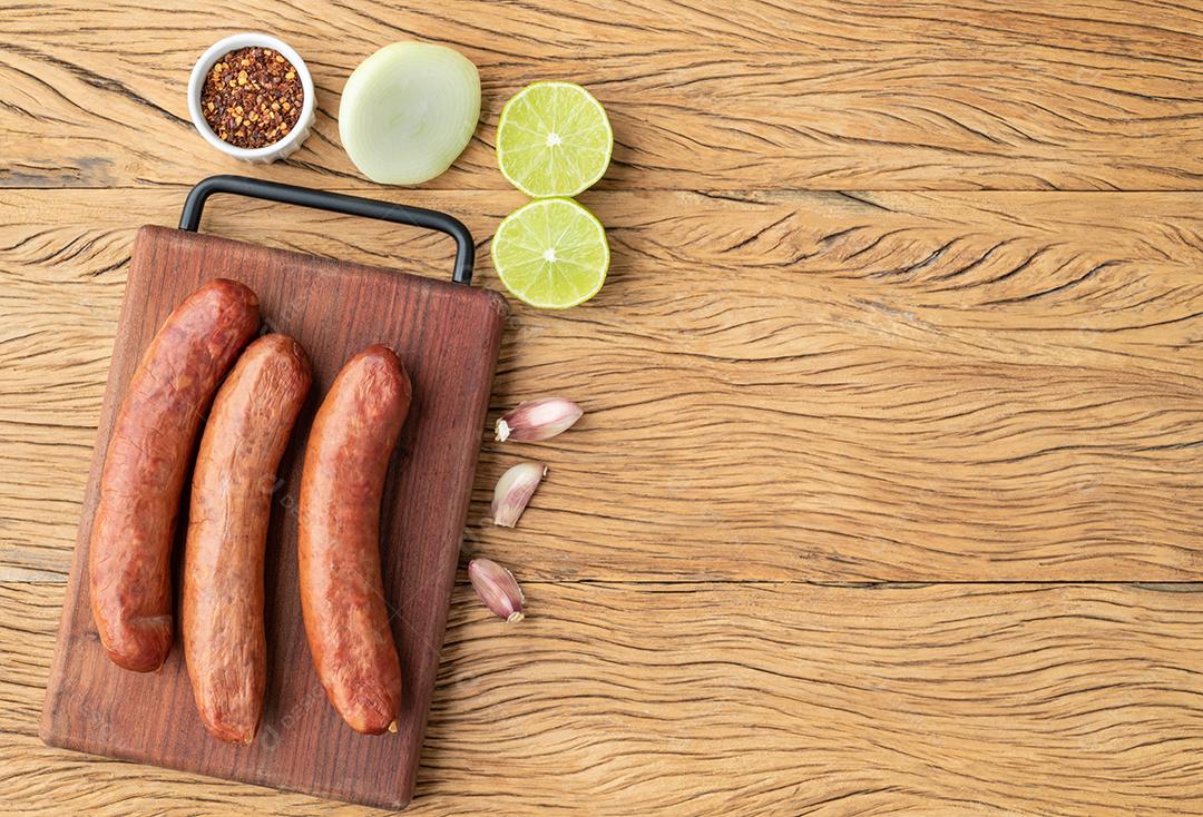 Salsicha de porco calabresa sobre placa de madeira com temperos