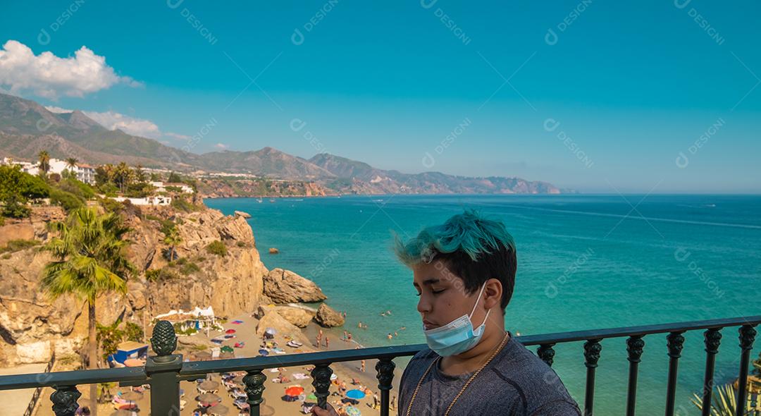 Bela vista do menino com cabelo azul com máscara abaixada na praia de Nerja.
