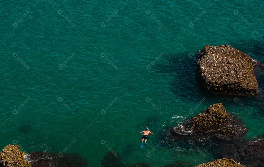 Vista aérea de cima da bela praia de Nerja, na Espanha, com um homem mergulhando