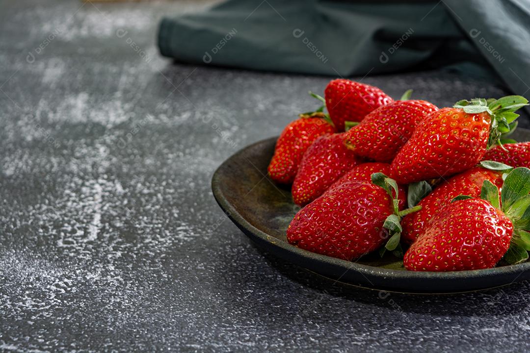 morangos deliciosos e vermelhos em ambiente dark food, preto.