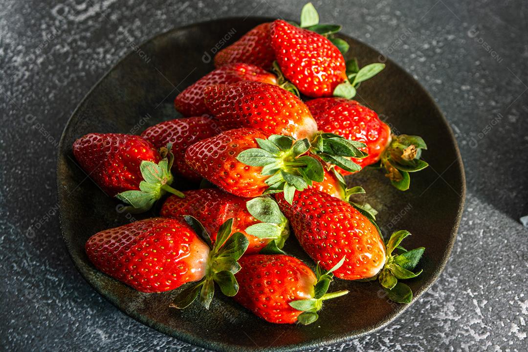 morangos deliciosos e vermelhos em ambiente dark food, preto.