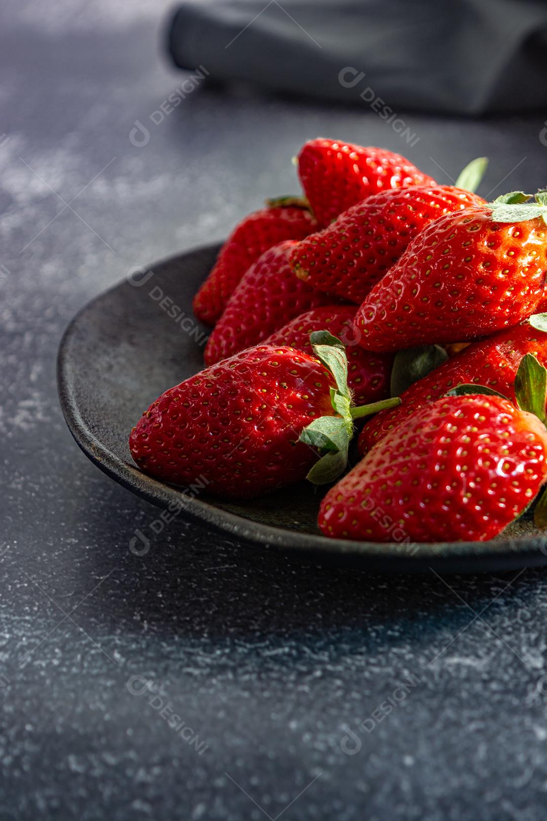 morangos deliciosos e vermelhos em ambiente dark food, preto.