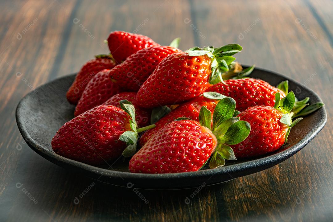 morangos deliciosos e vermelhos em ambiente dark food, preto.