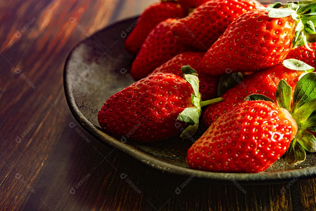 morangos deliciosos e vermelhos em ambiente dark food, preto.