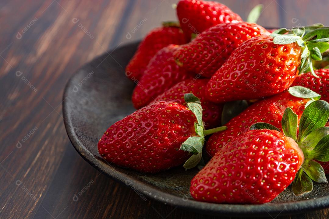 morangos deliciosos e vermelhos em ambiente dark food, preto.