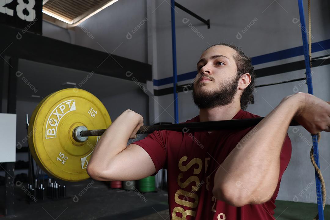 Homem jovem sobre uma academia fazendo musculações Conceito saude melhor