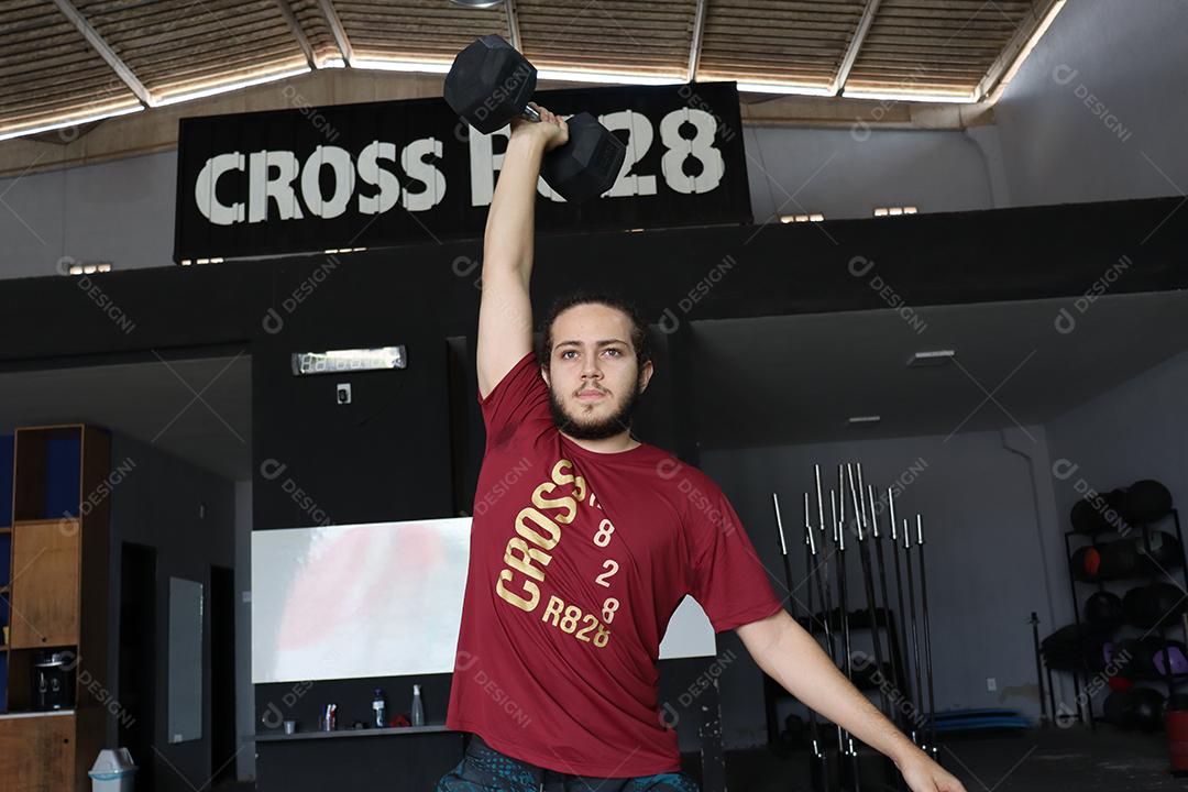 Homem jovem sobre uma academia fazendo musculações Conceito saude melhor