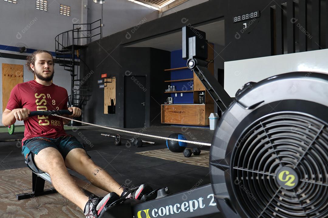 Homem jovem sobre uma academia fazendo musculações Conceito saude melhor