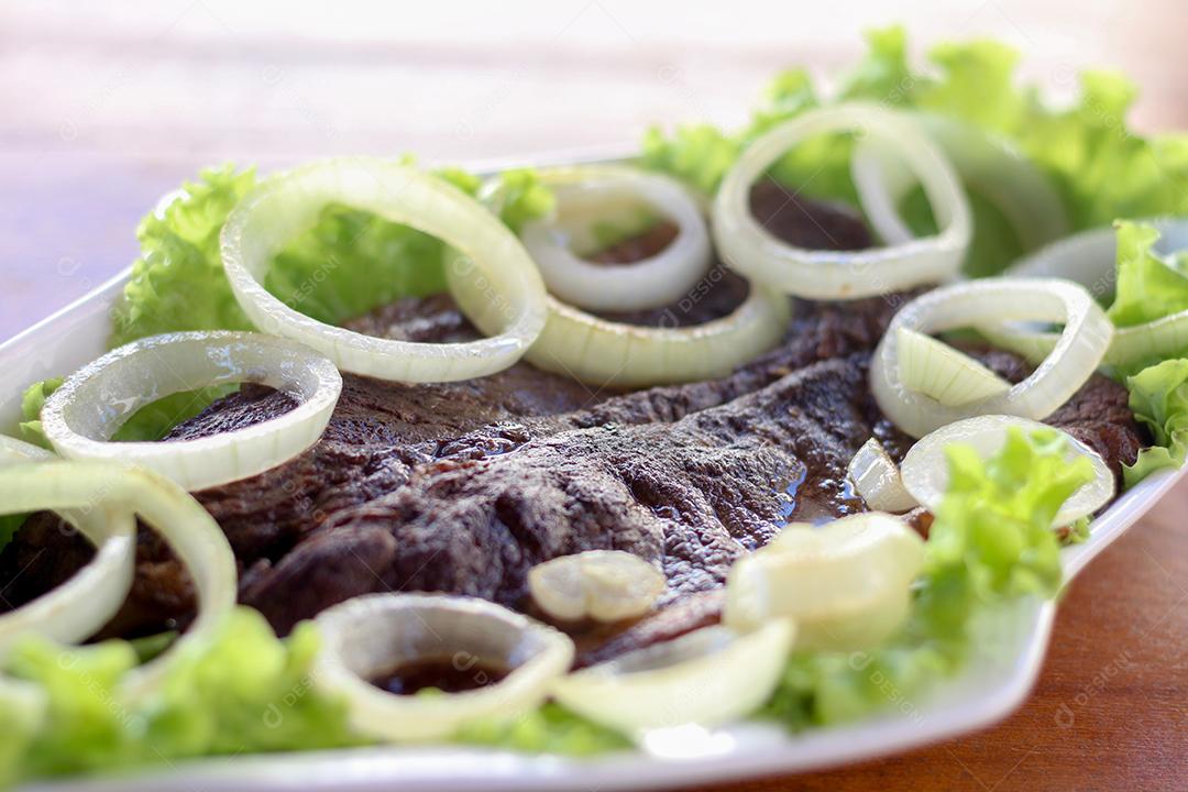 Prato de comida carne acebolada alface restaurante salada