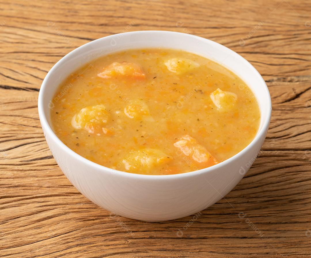 Sopa de legumes em uma tigela sobre a mesa de madeira.