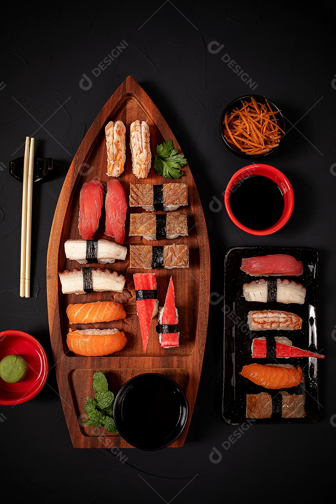 Mistura de comida japonesa, incluindo sushi e sashimi na barcaça de madeira.