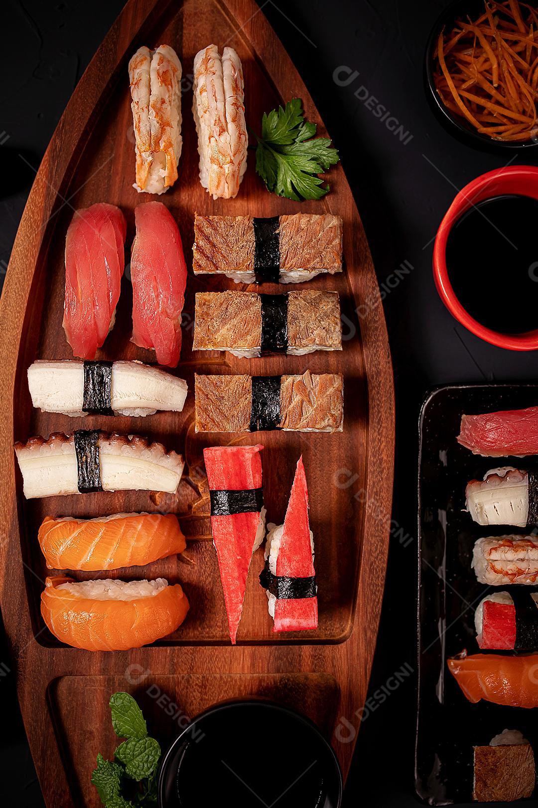 Mistura de comida japonesa, incluindo sushi e sashimi na barcaça de madeira.