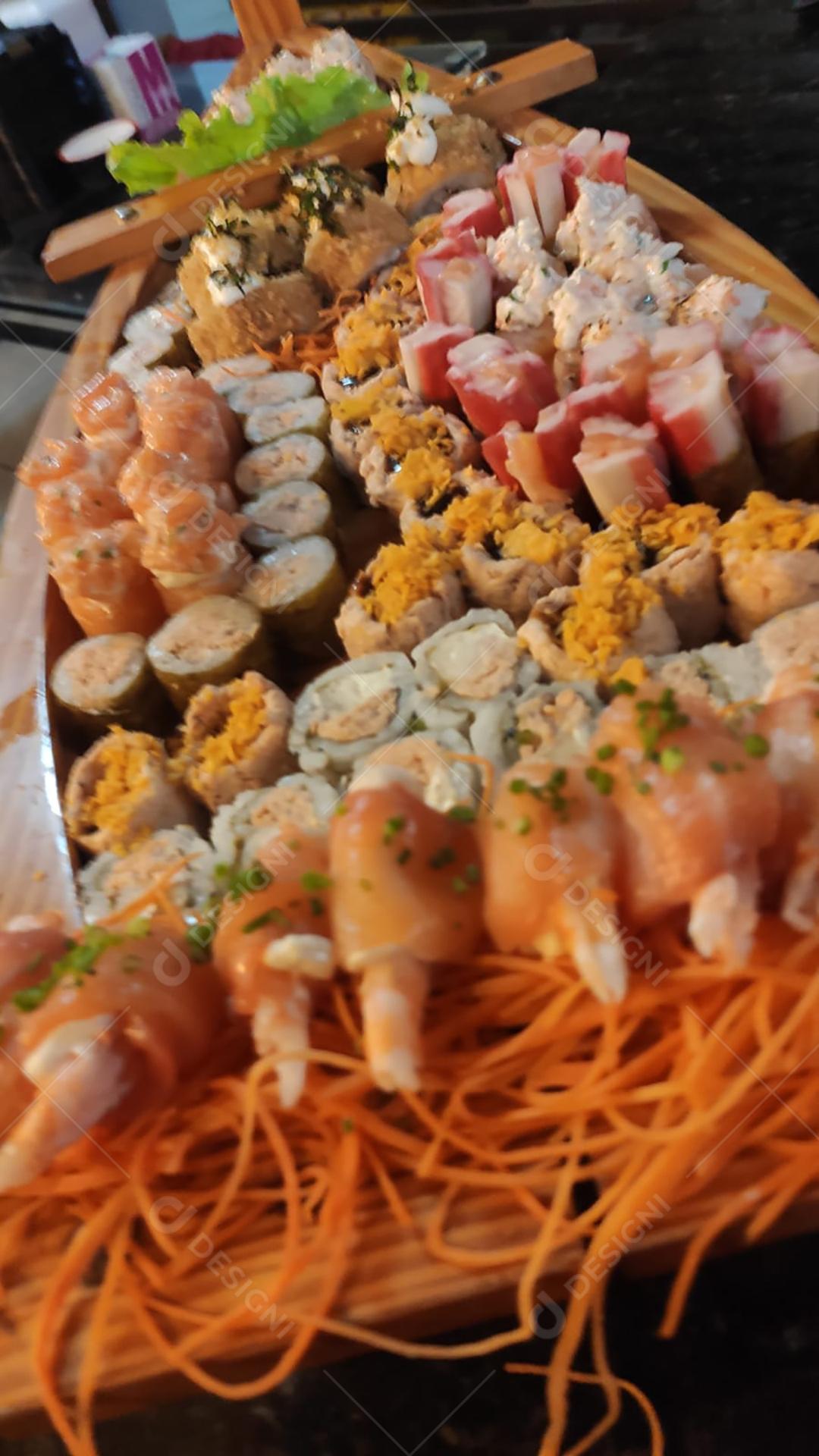 Mistura de comida japonesa, incluindo sushi e sashimi na barcaça de madeira.