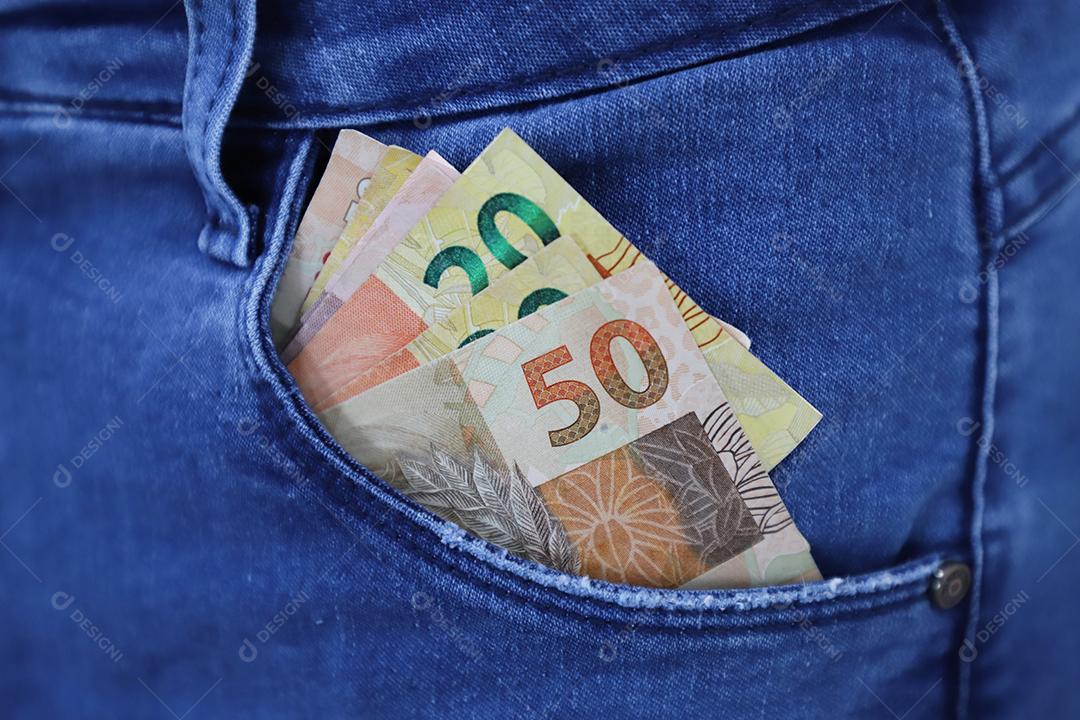 Dinheiro brasileiro real sobre um bolso de uma calça de uma pessoas brasileira