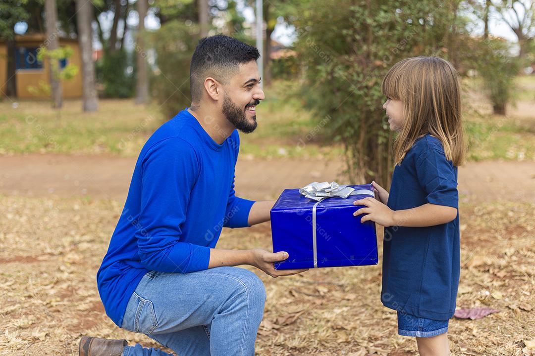 Este presente é para você papai. Menina entrega presente de dia dos pais ao pai no parque