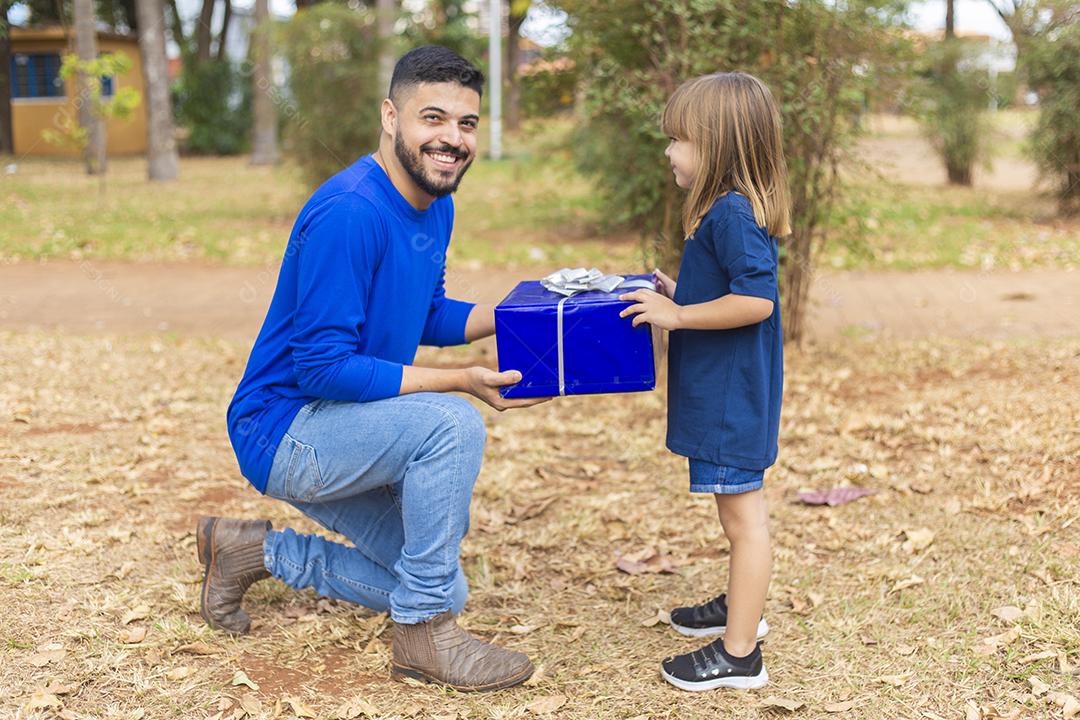 Este presente é para você papai. Menina entrega presente de dia dos pais ao pai no parque