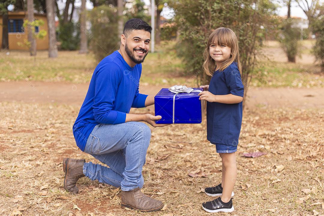 Este presente é para você papai. Menina entrega presente de dia dos pais ao pai no parque