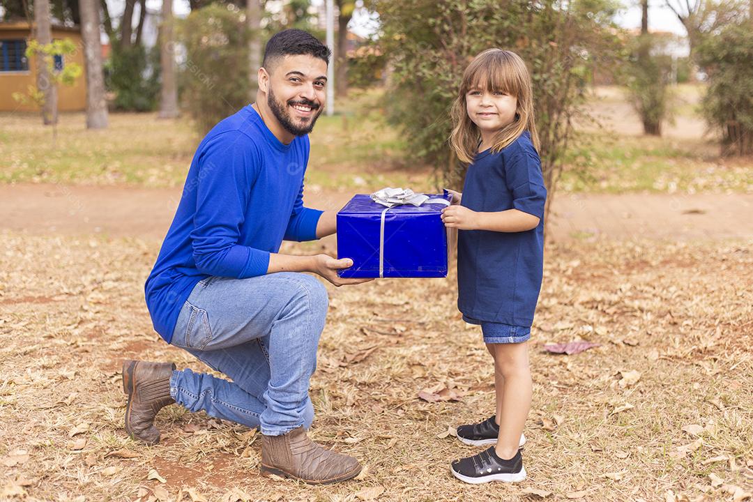 Este presente é para você papai. Menina entrega presente de dia dos pais ao pai no parque